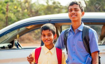 two indian boys ready to go to school on the car .